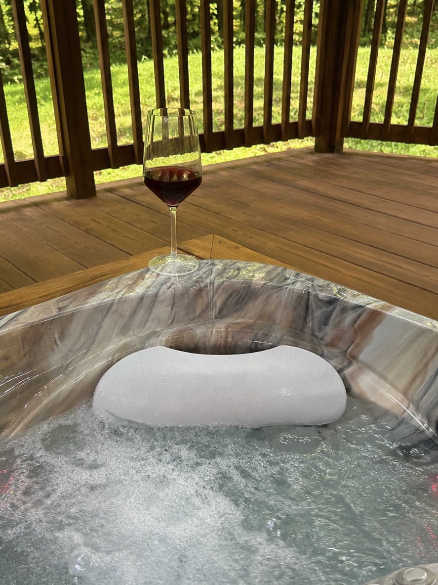 Hot tub bubbling under the pavilion with a glass of red wine on the ledge