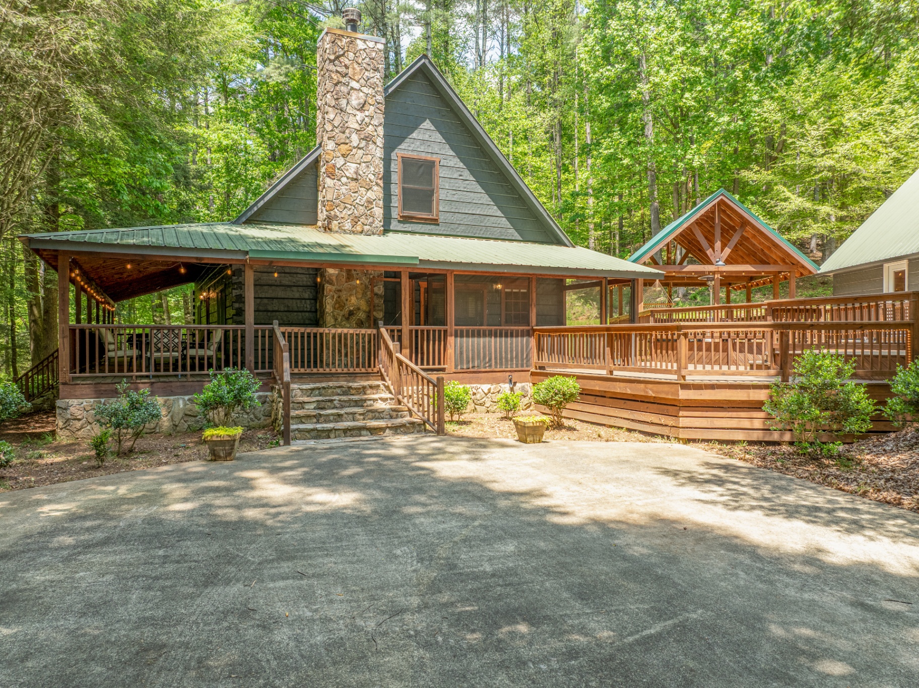 ElliJAYbird cabin exterior with deck, stone chimney and wooded setting