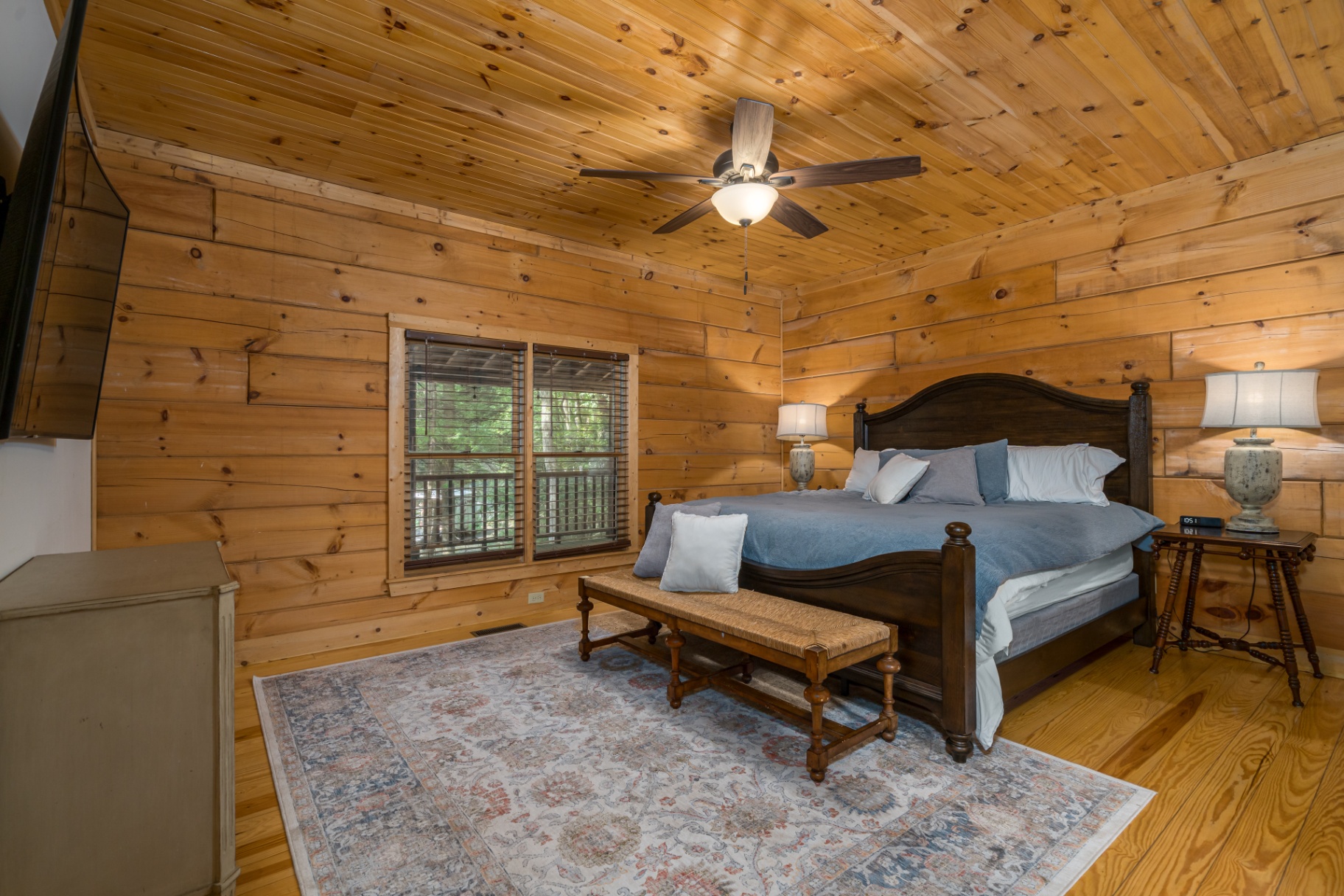 Master king bedroom with pine walls, blue bedding and forest-view windows