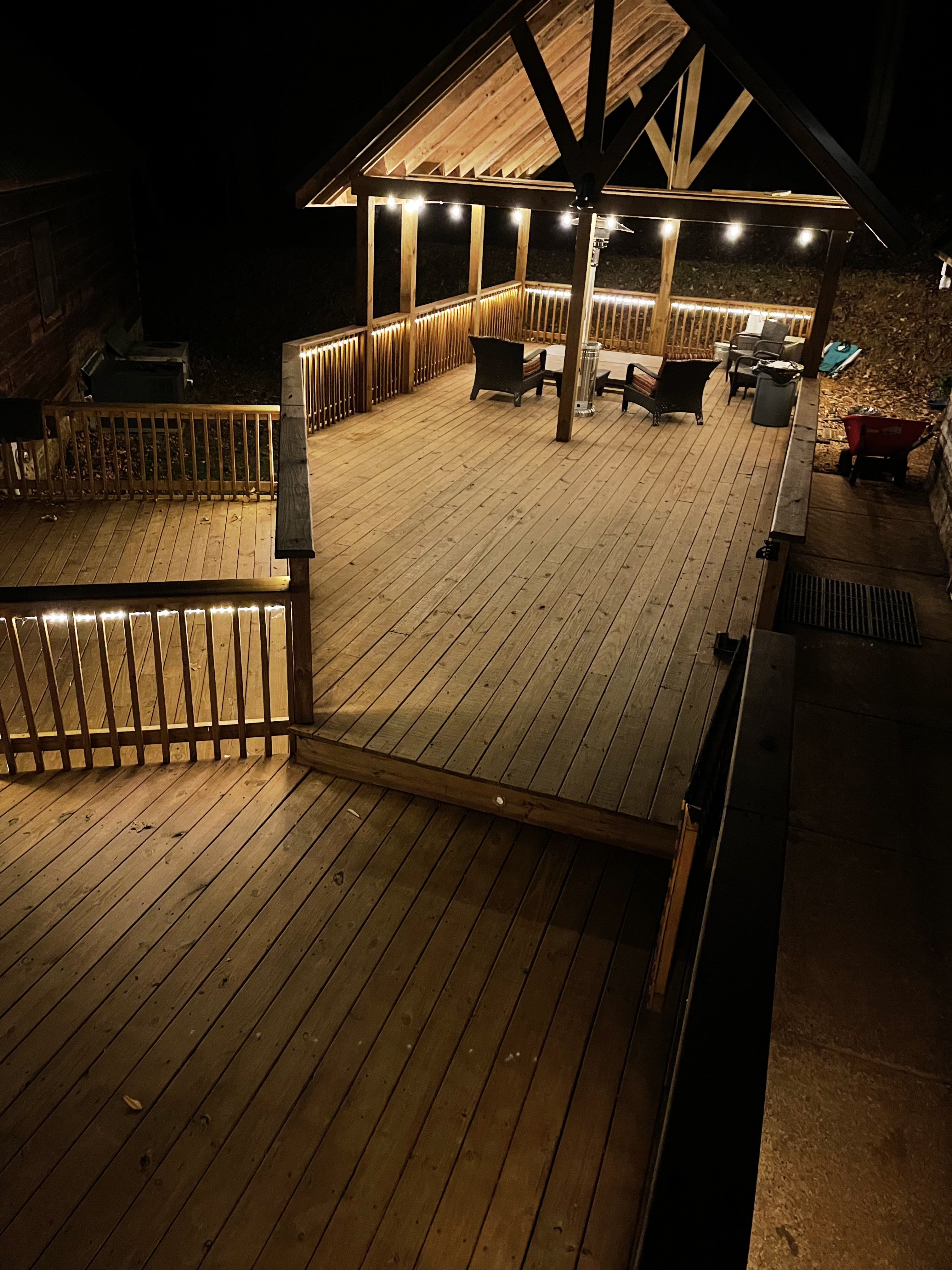 Wide view of the back deck at night with string lights and lounge seating