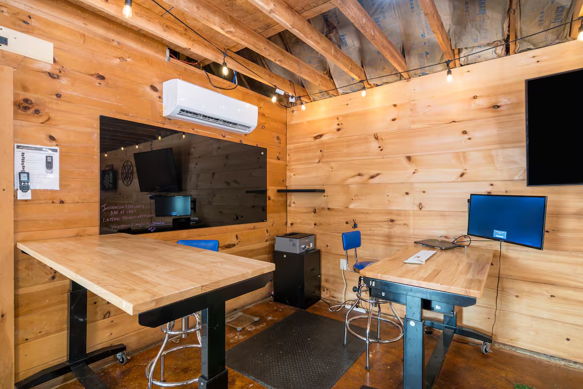 Game barn workspace with dual desks, monitors and dartboard