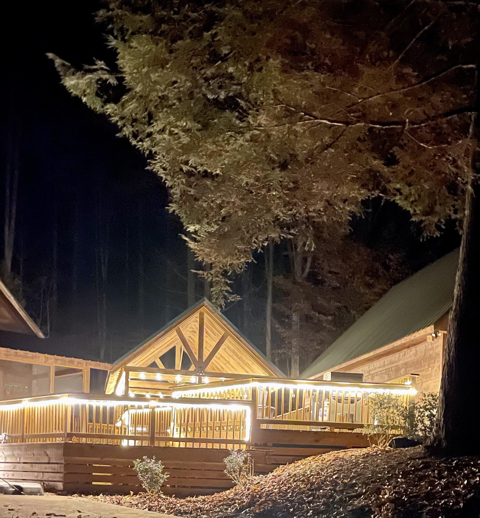 Front of the cabin at night lit by warm porch and deck lights