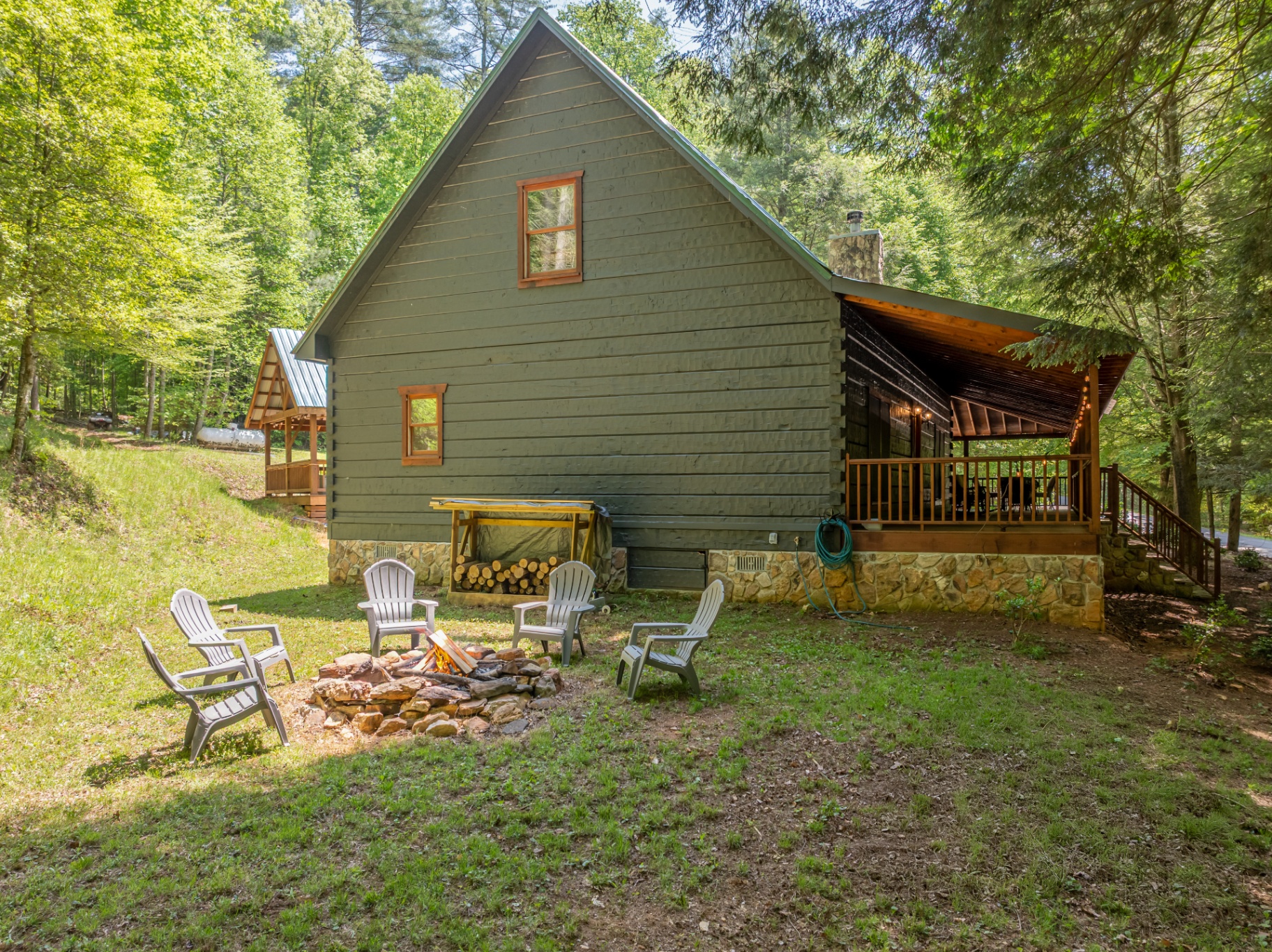 Backyard fire pit with chairs beside the cabin and covered porch